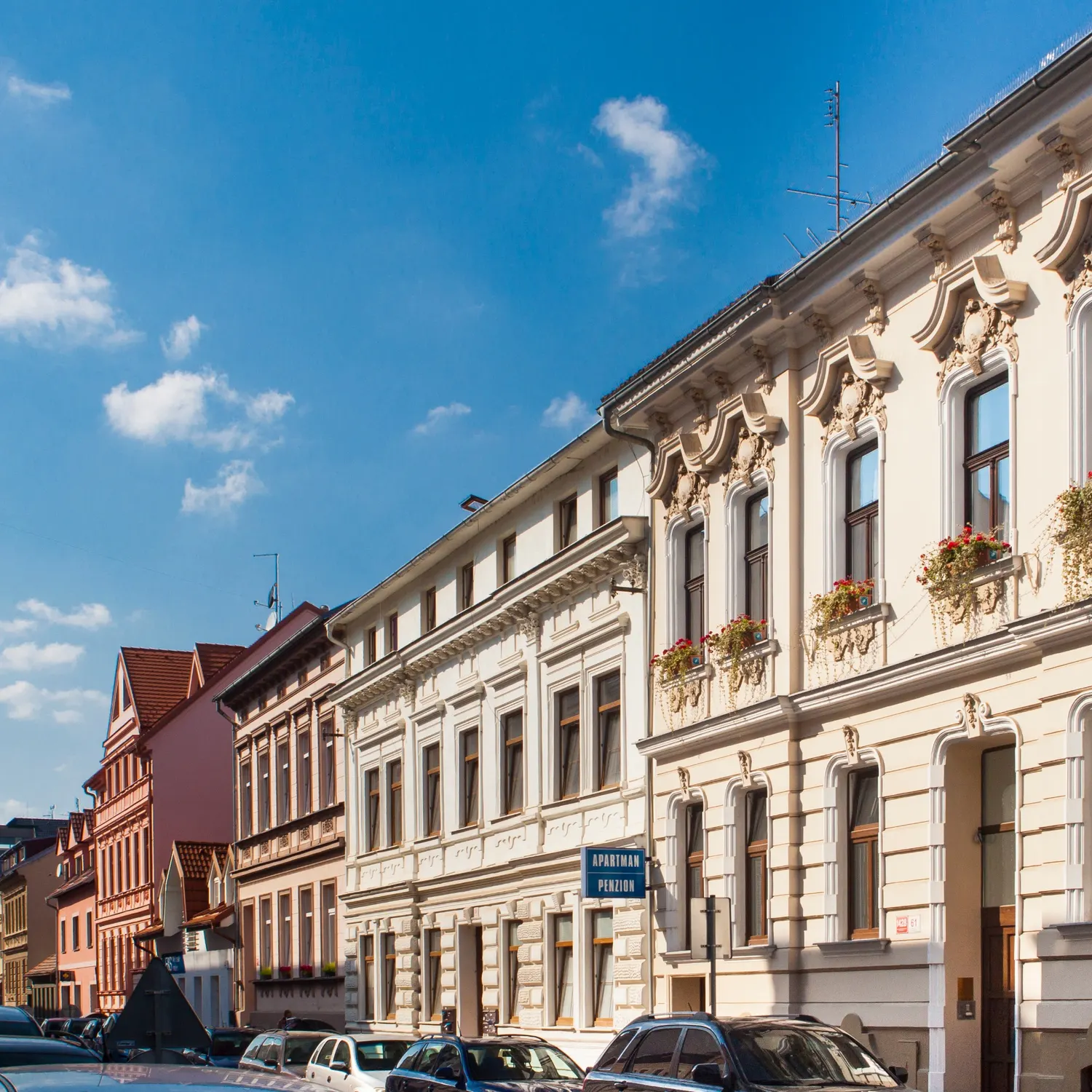 Pohled do ulice s cedulí penzionu pod modrým nebem
